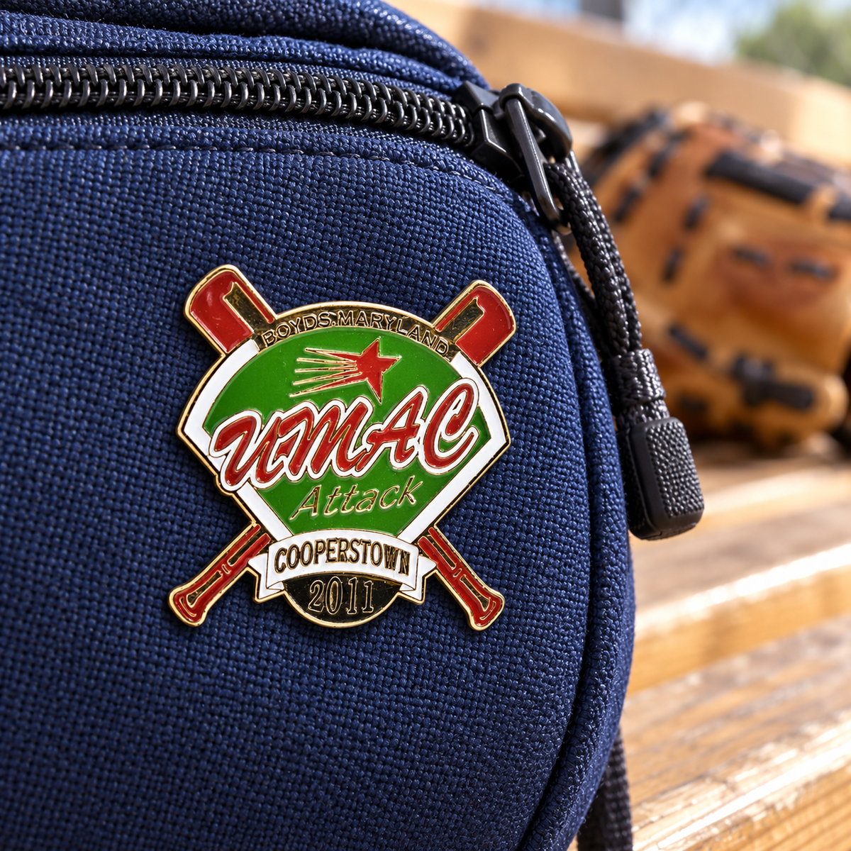 Custom enamel lapel pin worn on a baseball equipment bag — sample artwork lifestyle example