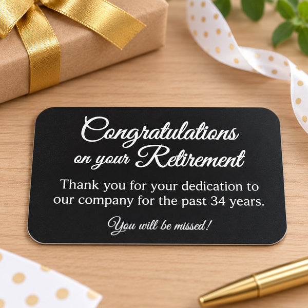 Black plastic plate with white retirement engraving beside gift wrapping supplies.
