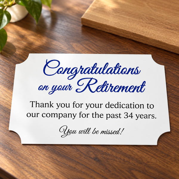 White printed retirement plate with notched corners beside a wooden display board.